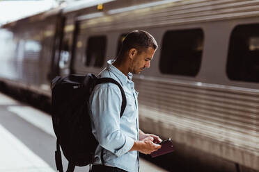 Tourist mit Rucksack und Smartphone auf dem Bahnsteig - MASF15787