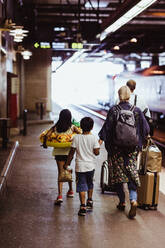 Familie in voller Länge mit Gepäck auf dem Bahnsteig eines Bahnhofs - MASF15789