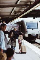 Mutter und Tochter unterhalten sich, während sie auf dem Bahnsteig mit dem Zug spazieren gehen - MASF15805