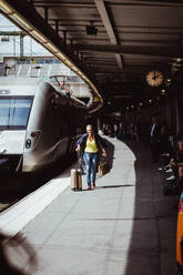 Glückliche Frau mit Gepäck, die auf dem Bahnsteig läuft, in voller Länge - MASF15811