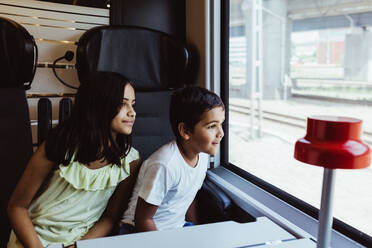 Geschwister schauen durch das Zugfenster, während sie zusammen reisen - MASF15848