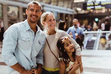 Lächelnde Eltern mit Tochter warten am Bahnhof - MASF15867