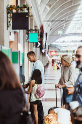 Mann mit Familie kauft Fahrkarten an einem Automaten im Bahnhof - MASF15869