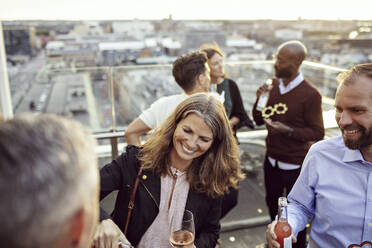 Happy male and female coworkers enjoying drinks in party after work - MASF15910