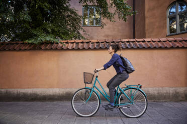 Seitenansicht einer Architektin beim Fahrradfahren auf einer Straße in der Stadt - MASF15935