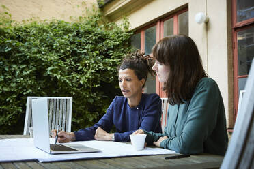 Female engineers planning over laptop at table in backyard - MASF15944