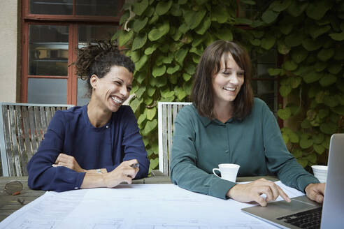 Female architect smiling while looking at laptop in backyard - MASF15945