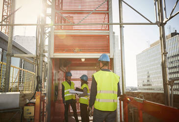 Male and female engineers at freight elevator in construction site - MASF15970