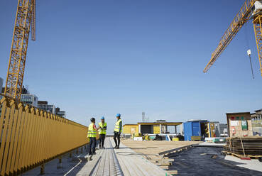 Männliche und weibliche Ingenieure diskutieren auf der Baustelle vor blauem Himmel - MASF15985