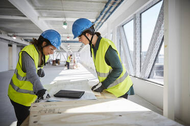 Side view of female engineers discussing over blueprint at construction site - MASF15989