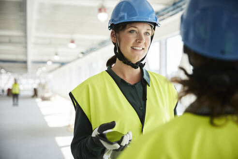 Selbstbewusste Ingenieurin im Gespräch mit einem Kollegen auf der Baustelle - MASF15990