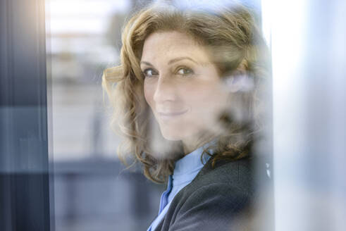 Porträt einer selbstbewussten Geschäftsfrau hinter einer Fensterscheibe - BMOF00080