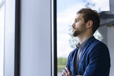 Young businessman leaning against the window - BMOF00104