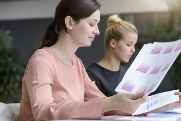 Young businesswoman with colleague reading documents in office - BMOF00120