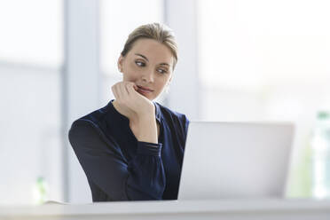 Businesswoman using laptop at desk in office - BMOF00132