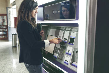 Frau beim Einführen der Karte in einen Geldautomaten - CAVF70989