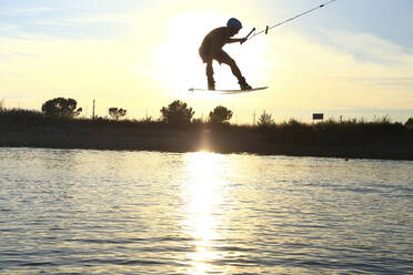 Man kiteboarding over lake against sky - CAVF71021