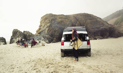 Seitenansicht einer Frau, die eine Tasche im Auto am Strand trägt - CAVF71044