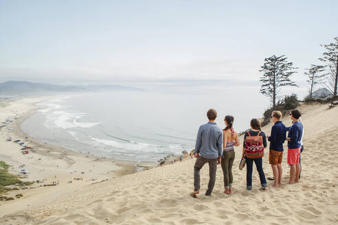 Freunde stehen zusammen auf Sand am Strand gegen den Himmel - CAVF71054