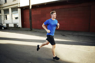 Young man jogging on street in city - CAVF71086