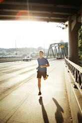 Sporty man jogging on bridge in city - CAVF71090