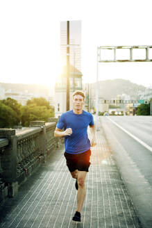 Porträt eines sportlichen Mannes, der auf einem Fußweg in der Stadt joggt - CAVF71104