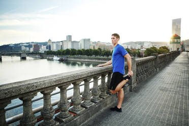 Sportlicher Mann beim Training auf einer Brücke in der Stadt - CAVF71105