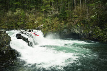 Man kayaking over waterfall in forest - CAVF71108