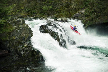 Kayaker descending from waterfall in forest - CAVF71110