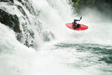 Whitewater kayaker paddling through river in forest - CAVF71112