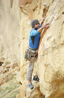 Entschlossener Mann klettert auf Felsen - CAVF71119