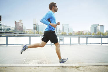 Male athlete jogging on promenade in city - CAVF71132