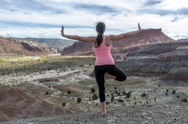 Rear view of woman exercising on rock formations - CAVF71160