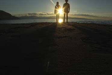 Silhouette couple standing on sand by lake during sunset - CAVF71203