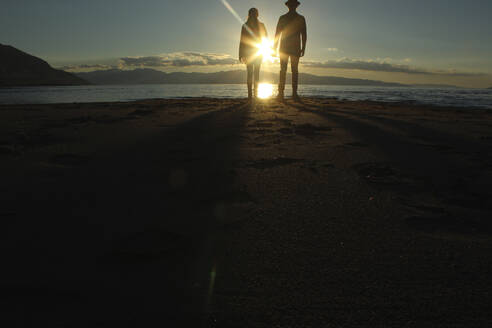 Silhouette Paar steht auf Sand am See bei Sonnenuntergang - CAVF71203