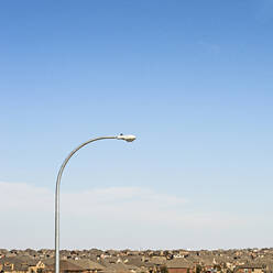 Straßenlaterne inmitten von Häusern vor blauem Himmel in der Stadt - CAVF71222