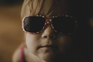Close-up portrait of cute baby girl in sunglasses at home - CAVF71223