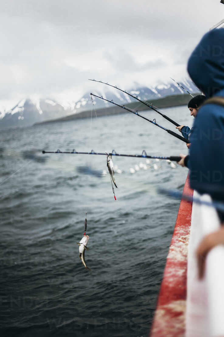 People fishing while traveling in boat on sea against sky stock photo
