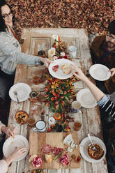 Hoher Blickwinkel von Freunden beim Essen am Tisch, die auf einem Feld sitzen - CAVF71298