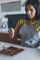 Frau, die in der Küche Schokoladentafeln garniert - CAVF71316