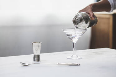 Cropped image of woman hand pouring alcohol in martini glass - CAVF71319