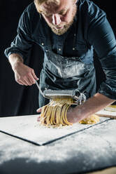 Hobby chef making fresh tagliatelle with pasta machine - JOSF04107