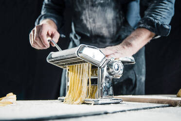 Hobby chef making fresh tagliatelle with pasta machine - JOSF04109