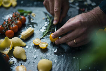 Hand chopping tomatoes on platter with pasta and herbs - JOSF04116