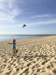 Frankreich, Nouvelle-Aquitaine, Gironde, Pyla sur Mer, Frau wirft Strohhut an der Dune du Pilat - GWF06335