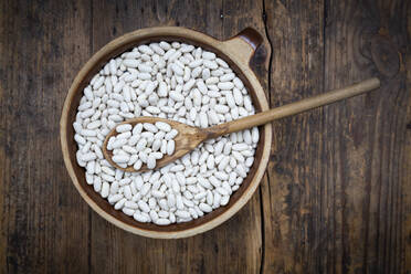 Overhead view of bowl of white cannellini beans on wooden table - LVF08475