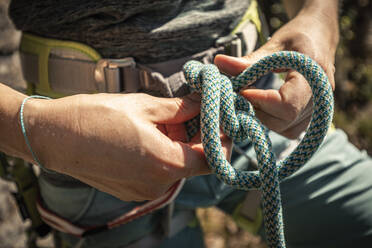 Frau bereitet sich auf das Klettern vor, prüft Seil, Achterknoten - MSUF00070