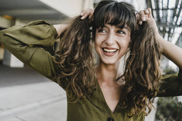 Portrait of smiling brunette woman, holding braids - KNSF06982