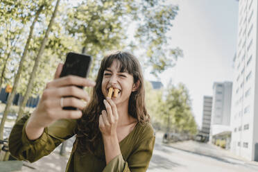 Porträt einer brünetten Frau, die ein Selfie macht, Kaninchenzähne mit Pommes frites - KNSF06985