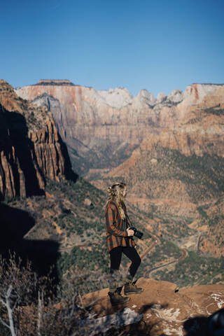 Junges Mädchen posiert mit einer Kamera mit Zion National Park als Hintergrund, lizenzfreies Stockfoto